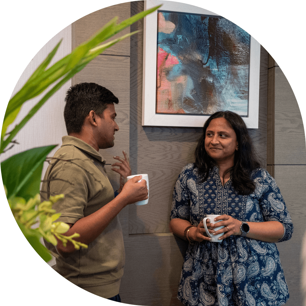 Two colleagues at Fire standing together with coffee, chatting.